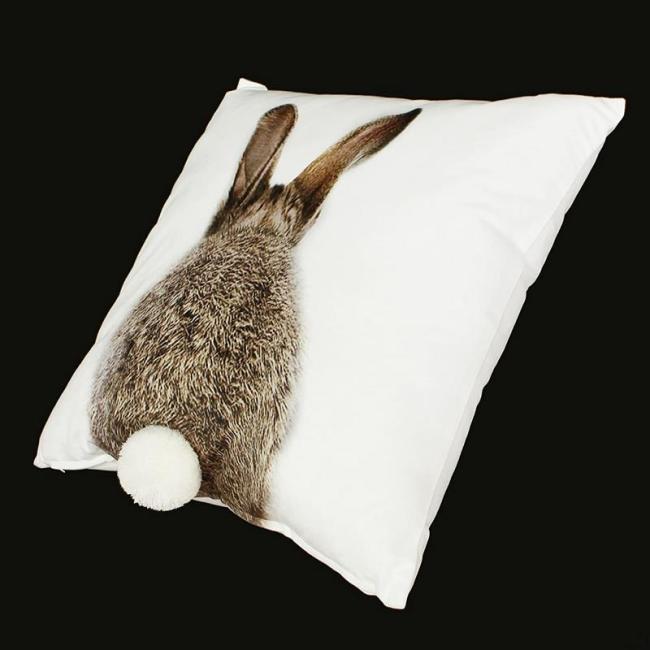Kissenhülle in weiß mit Hasenmotiv und angenähntem Pompom-Schwänzchen, seitlich schräg aufgenommen