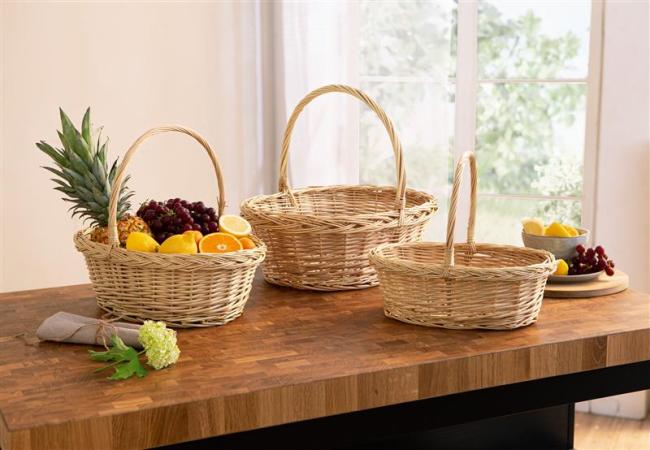 Bügelkorb aus heller Weide, alle 3 Größen zusammen auf einem dunklein Holztisch, dekoriert mit Obst