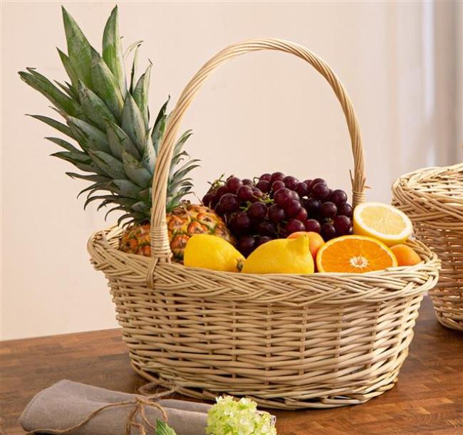 Preview: Bügelkorb aus heller Weide, mittel, gefüllt mit Obst, auf einem dunklen Holztisch 